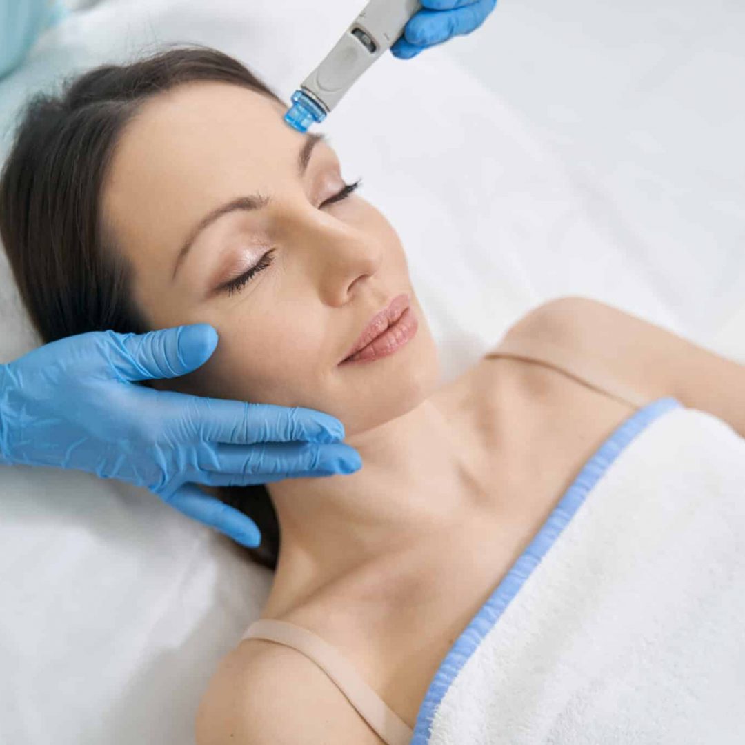 Close up of doctor beautician cleaning female face with microdermabrasion hydro device while performing hydrafacial treatment